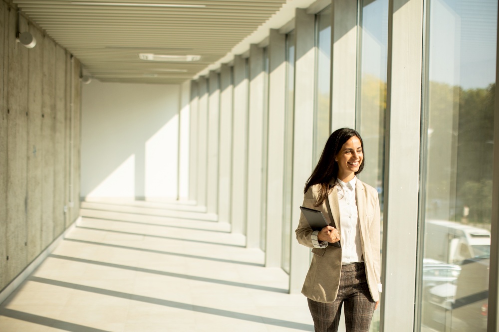 Young businesswoman walking on modern office hallway on a sunny day