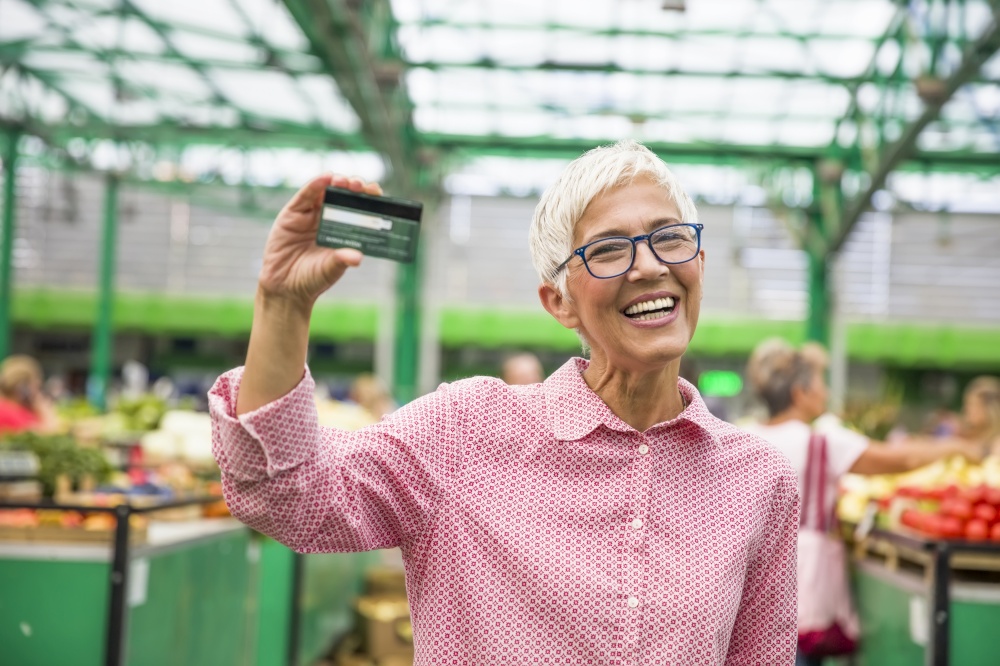 Portrait of senior woman holds credit card on market