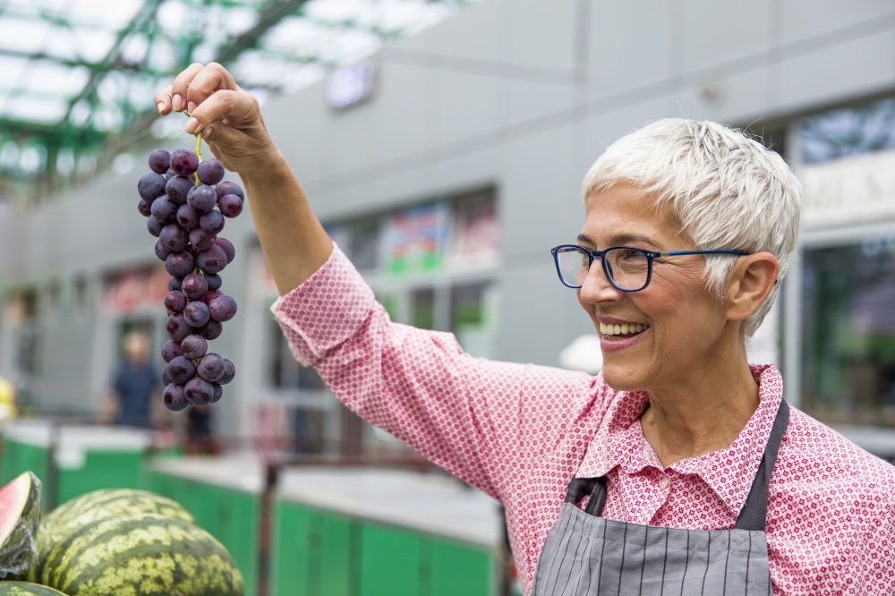 Portrait of senior woman sells grapes on market