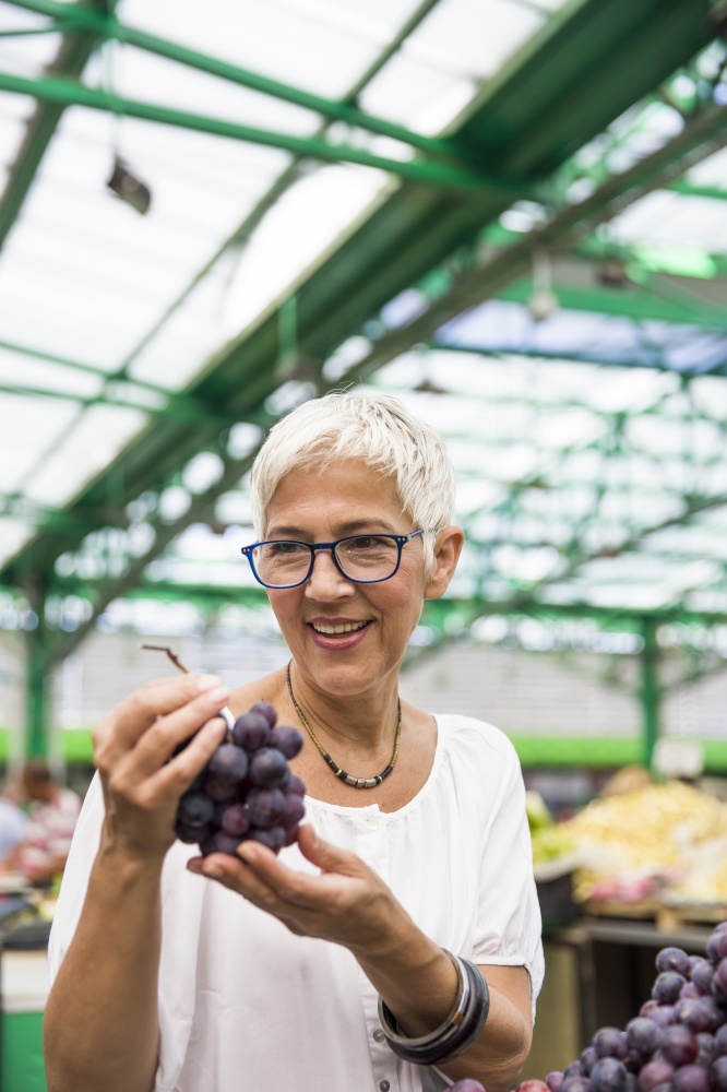 Portrait of senior woman buying grape on market