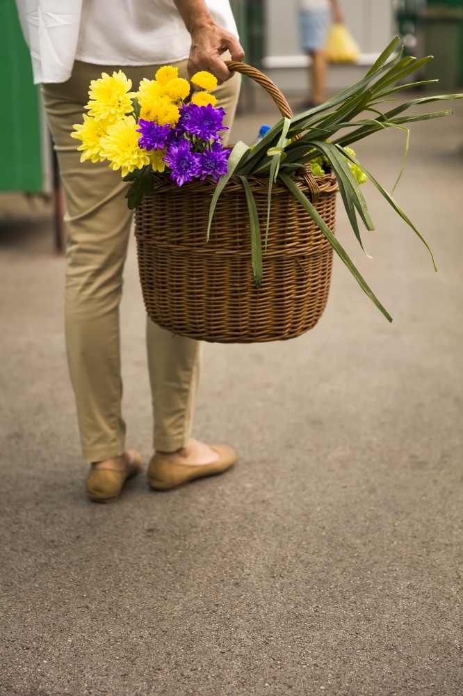 Woman holds a basket with flowers on market