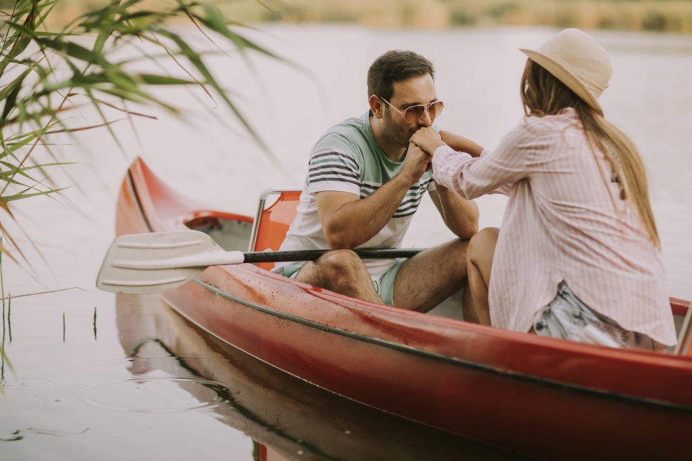 Loving man kissing hands to his woman in boat on the lake at summer day