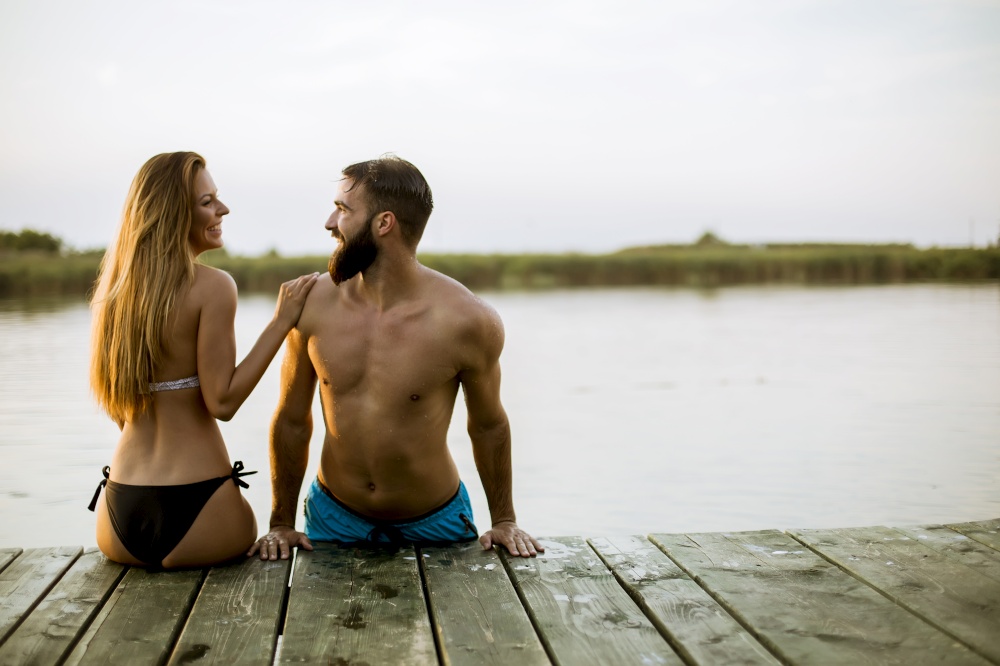 Young sensual romantic couple in love on pier at the lake outdoor in summer day