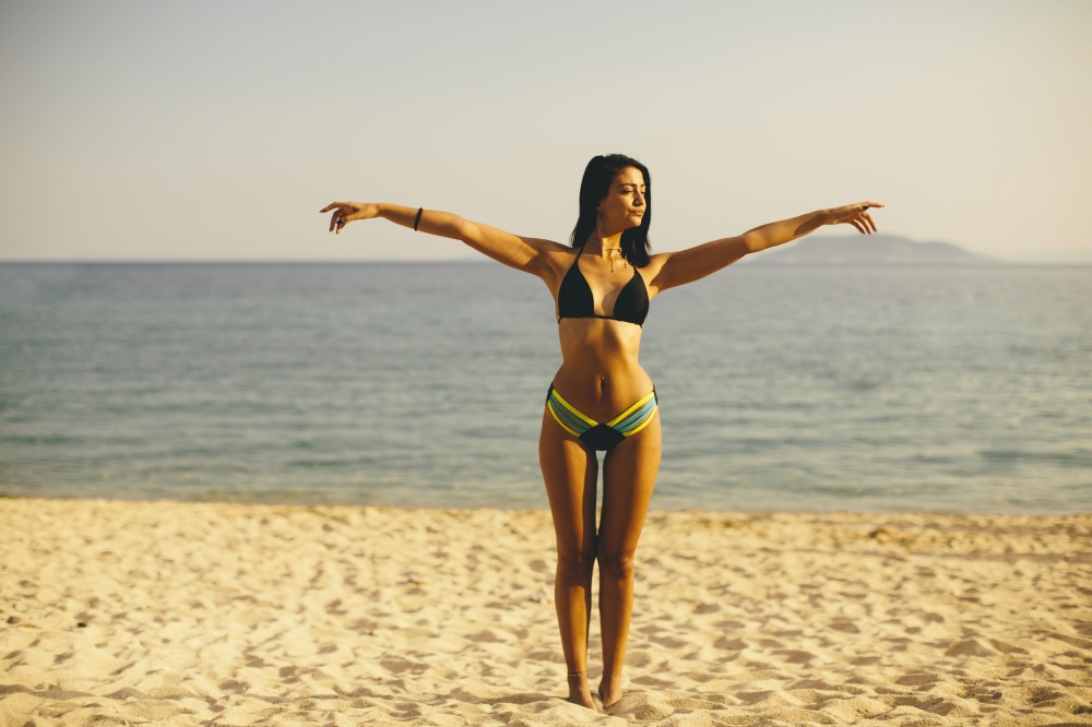 Young woman standing on the beach in a bikini