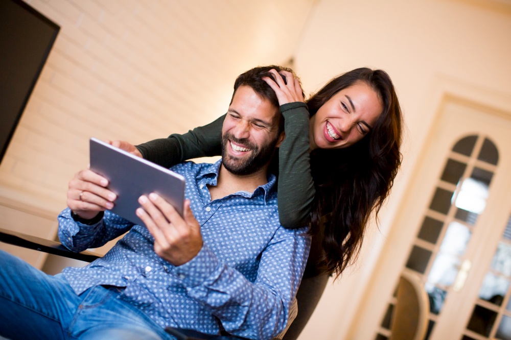 Portrait of young couple sitting in the living room and using tablet