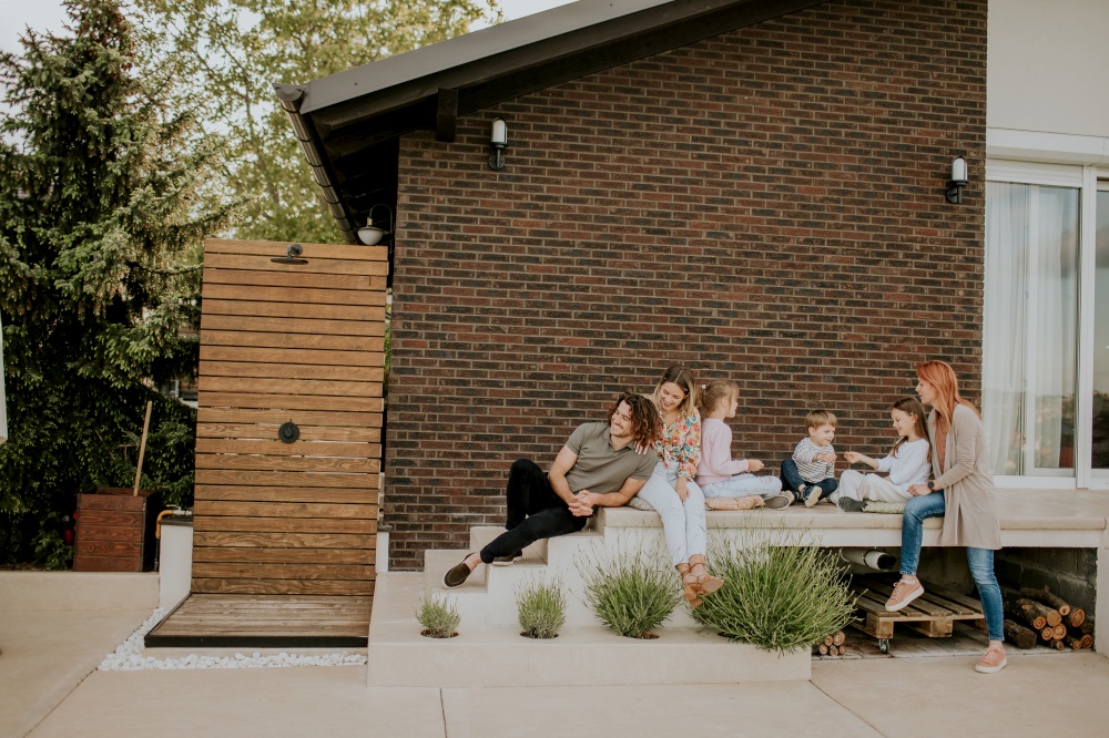 Happy group of young people and kids having good time in the house backyard