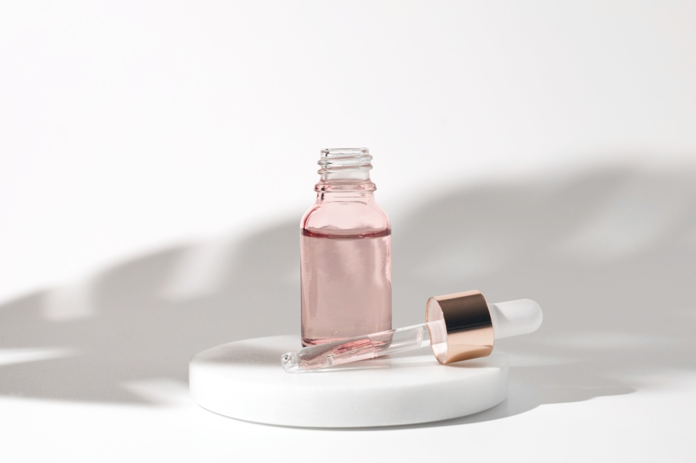 Pink glass bottle of cosmetic liquid transparent gel on white background. Dropper bottle, hyaluronic acid, oil, serum, skin care product. Pink glass bottle of cosmetic liquid transparent gel on white background. Dropper bottle, hyaluronic acid, oil, serum, skin care product.