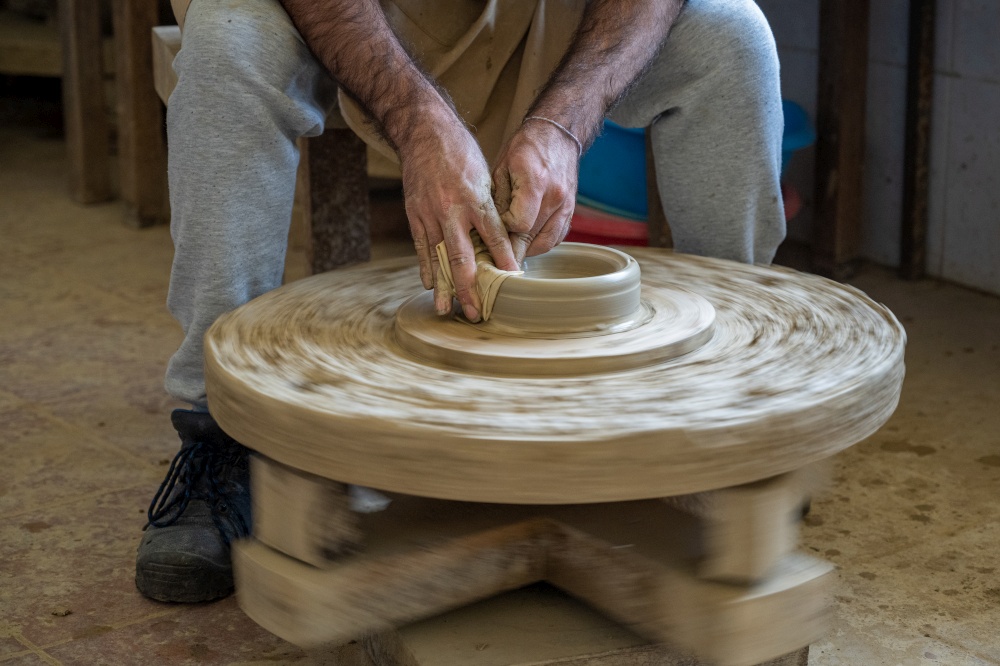 Potter shaping a piece of clay on a low wheel in Amarante, Portugal.
