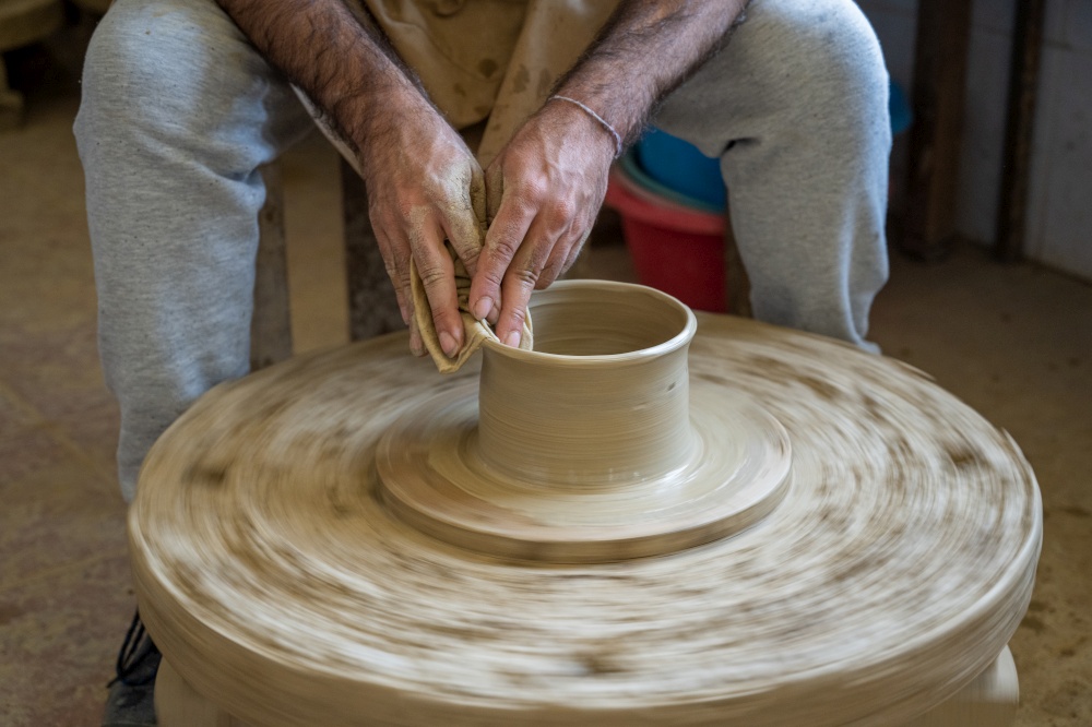 Potter shaping a piece of clay on a low wheel in Amarante, Portugal.