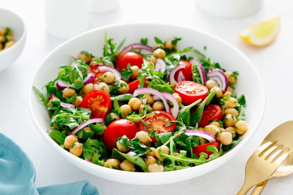 Vegetarian chickpea salad with tomatoes, arugula, parsley, spinach and red onion. Healthy food, diet