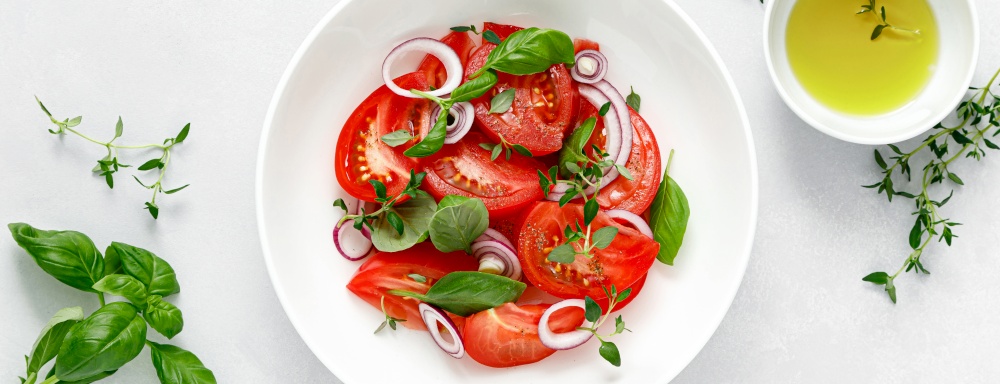 Salad with red ripe tomatoes, basil and olive oil. Top view. Banner
