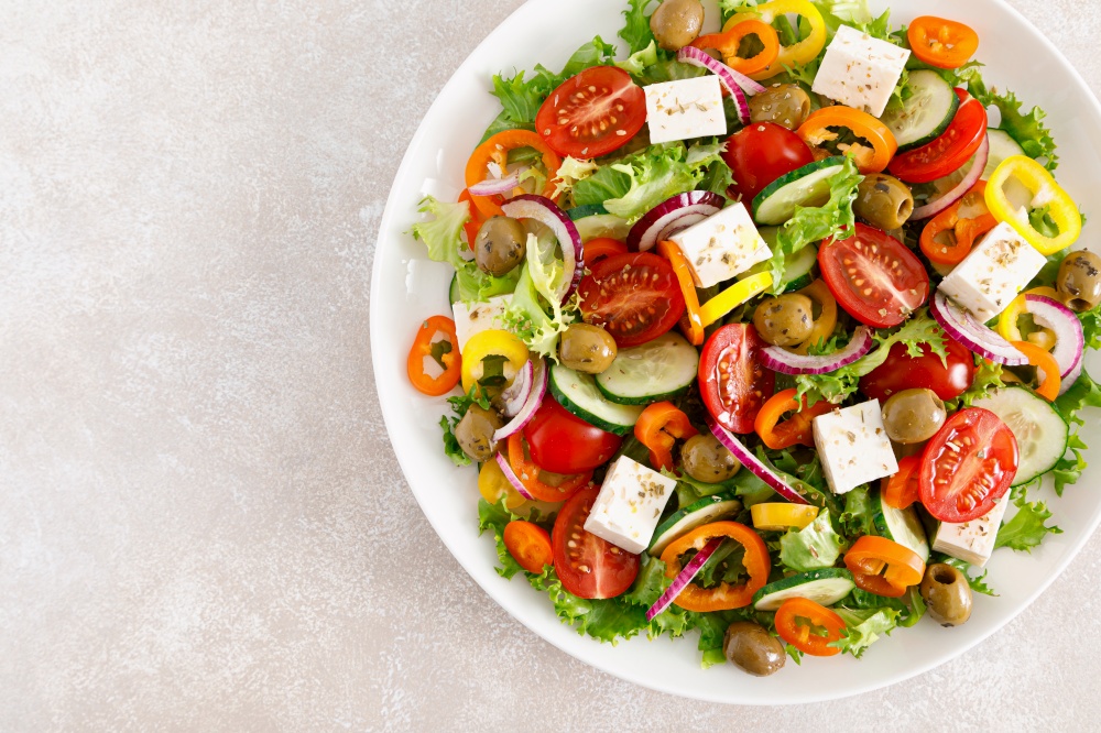 Greek salad with feta cheese, tomatoes, cucumbers, pepper, red onion and green olives. Top view