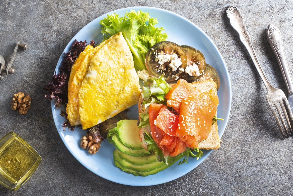 omelette with salmon and fresh avocado on plate. omelette with salmon and avocado for lunch