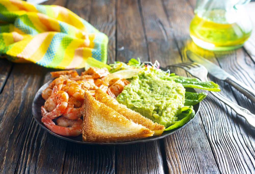 fried shrimps with fresh avocado and toasts. helthy breakfast. fried shrimps with avocado and toasts