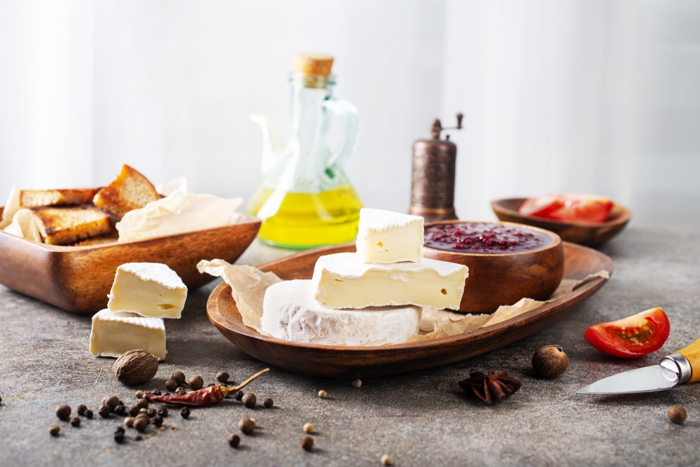 Camembert cheese with figs, raspberry jam. Round brie or camambert cheese on cutting board