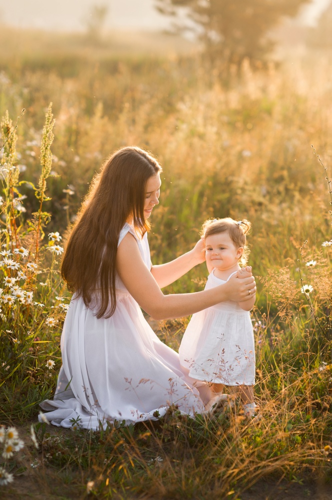 The girl and her mother bask in the spring sunshine.. Mother and daughter in sunny photos play among dandelions 3020.