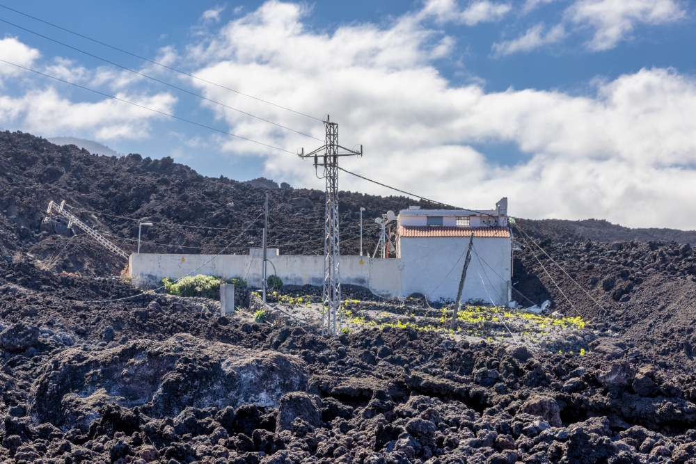 House been spared while fully surrounded by new lava field from recent erupted volcano Cumbre Vieja at la Palma. House fully surrounded by lava from volcano at la Palma