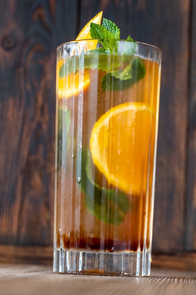 Glass of Dutch Orange Cup cocktail garnished with orange slice and fresh mint leaves