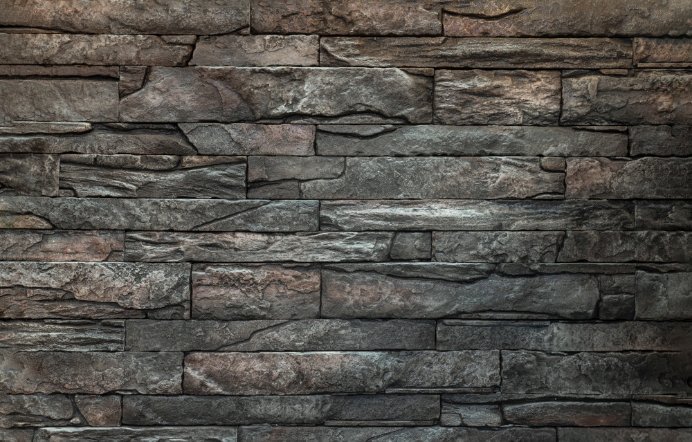 Soft light on pieces of Stone cladding wall. made of striped stacked slabs of natural brown rocks for walls texture and background, Copy space, Selective focus.