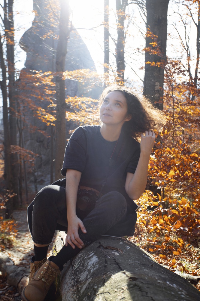 tourist girl sitting on a log in the autumn forest. Carpathians mountains.