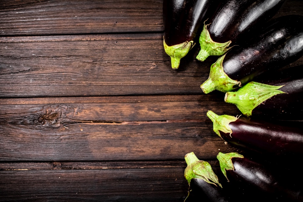 Fresh eggplants are in a row on the table. On a wooden background. High quality photo. Fresh eggplants are in a row on the table.