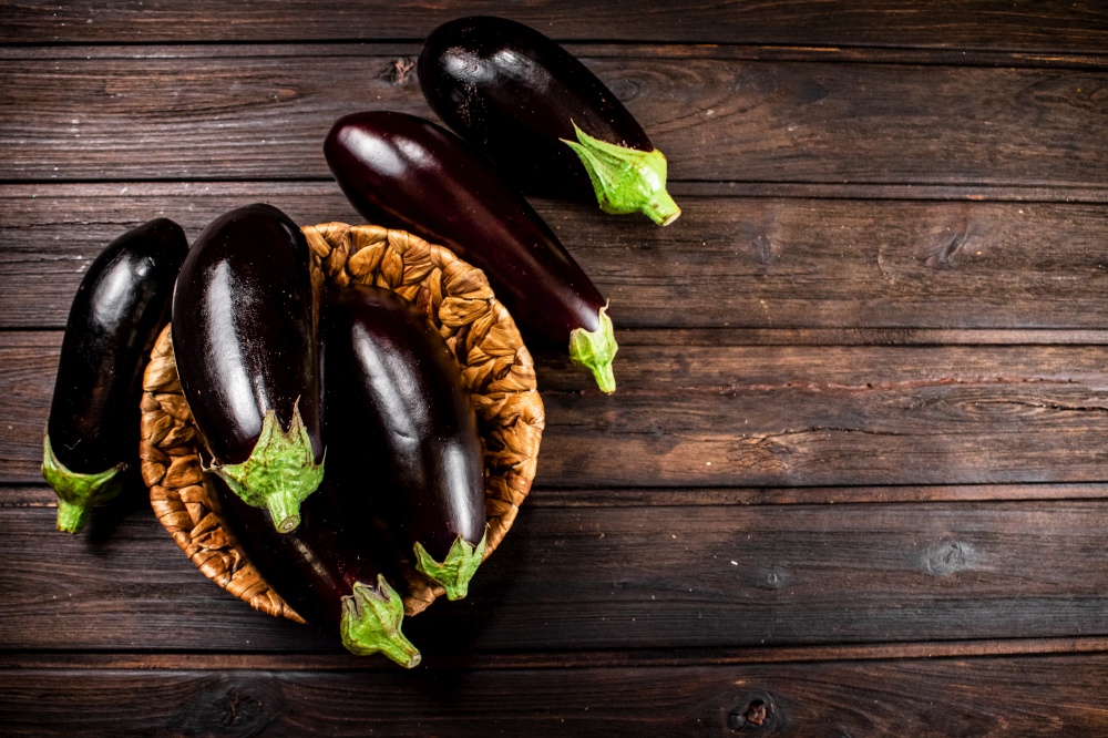 Ripe eggplant in a basket on the table. On a wooden background. High quality photo. Ripe eggplant in a basket on the table.