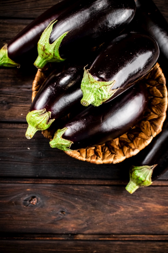 Ripe eggplant in a basket on the table. On a wooden background. High quality photo. Ripe eggplant in a basket on the table.