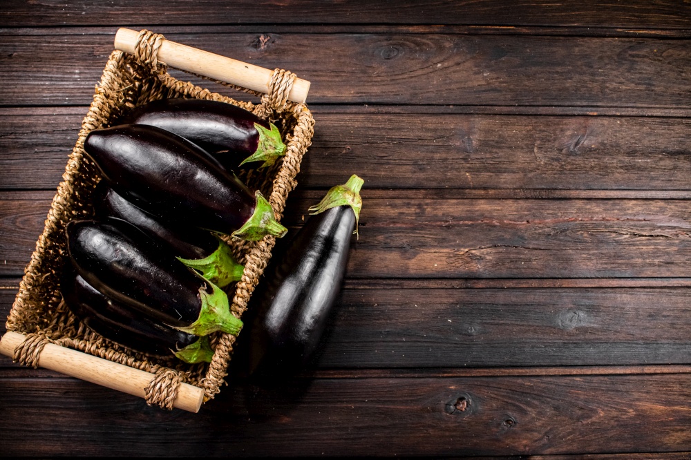 Box on a table with ripe eggplant. On a wooden background. High quality photo. Box on a table with ripe eggplant.