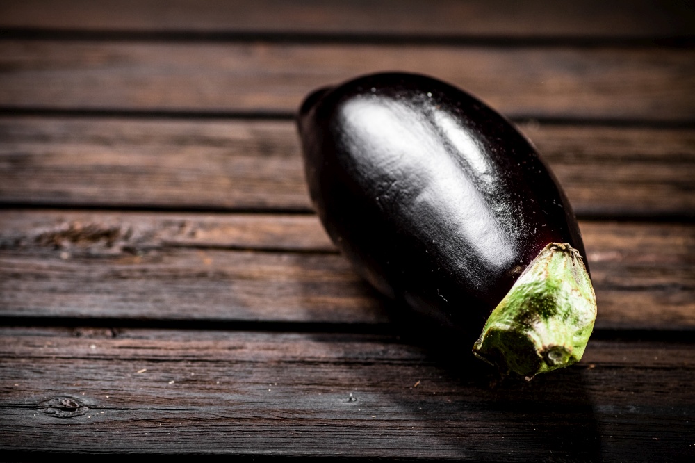 One fresh eggplant on the table. On a wooden background. High quality photo. One fresh eggplant on the table.