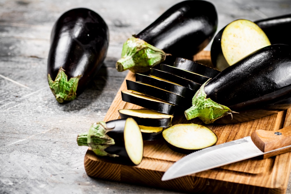 Cut into pieces of ripe eggplant on a wooden cutting board. On a gray background. High quality photo. Cut into pieces of ripe eggplant on a wooden cutting board.