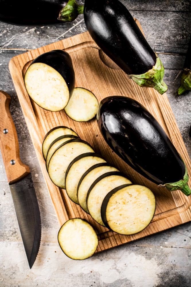 Cut into pieces of ripe eggplant on a wooden cutting board. On a gray background. High quality photo. Cut into pieces of ripe eggplant on a wooden cutting board.