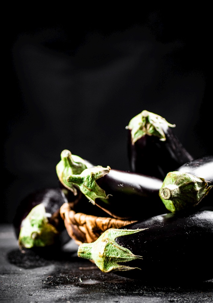 A full basket of fresh eggplant on the table. On a black background. High quality photo. A full basket of fresh eggplant on the table.