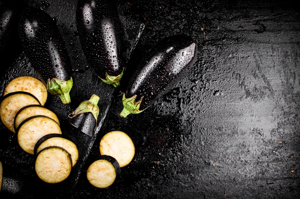 Pieces of ripe eggplant on a stone board. On a black background. High quality photo. Pieces of ripe eggplant on a stone board.