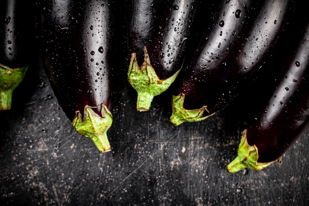 Fresh wet eggplant on the table. On a black background. High quality photo. Fresh wet eggplant on the table.