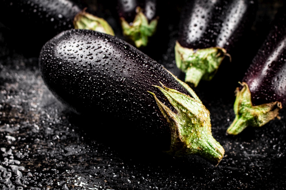 Fresh wet eggplant on the table. On a black background. High quality photo. Fresh wet eggplant on the table.