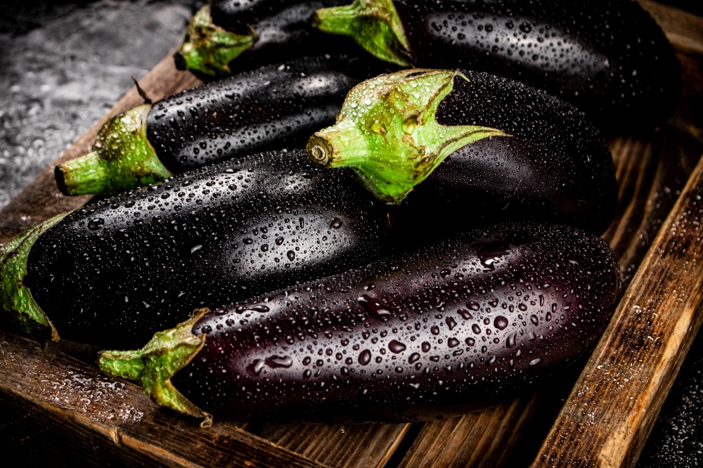 Ripe eggplant on a wooden tray. On a black background. High quality photo. Ripe eggplant on a wooden tray.