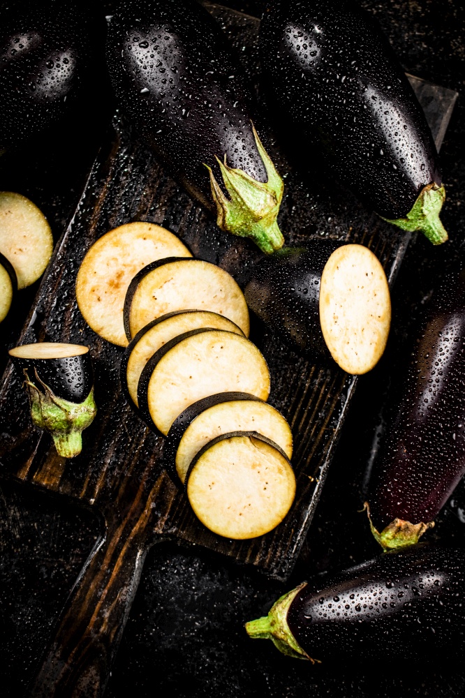 Cut into pieces on a cutting board of eggplant. On a black background. High quality photo. Cut into pieces on a cutting board of eggplant.