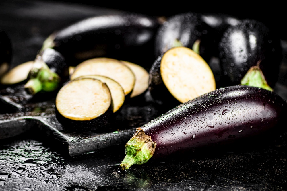 Cut into pieces on a cutting board of eggplant. On a black background. High quality photo. Cut into pieces on a cutting board of eggplant.