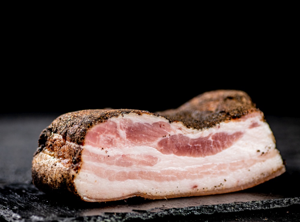 A piece of homemade pork lard. On a black background. High quality photo. A piece of homemade pork lard.