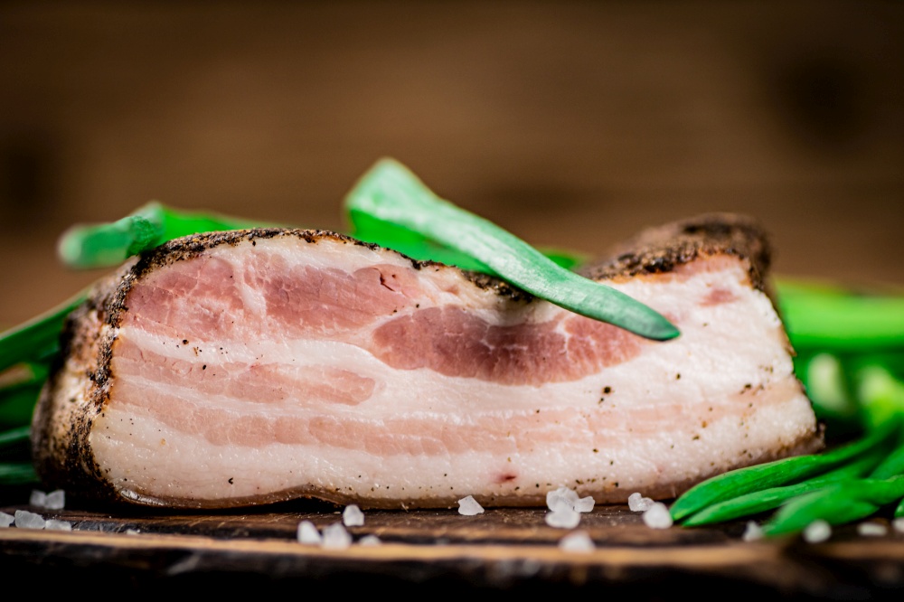 Delicious pork lard with green onions. On a wooden background. High quality photo. Delicious pork lard with green onions.