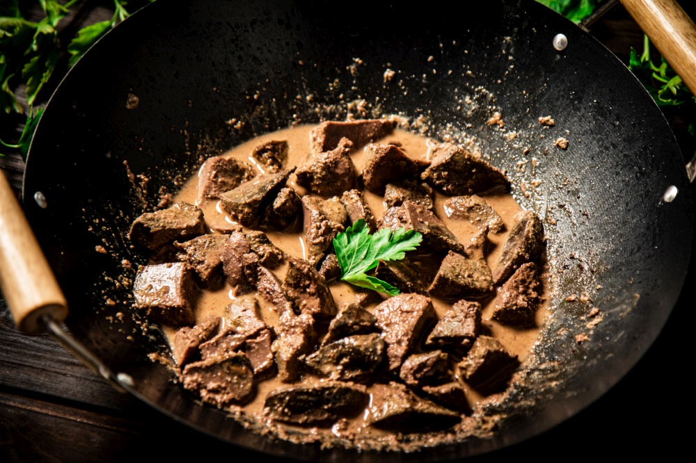 Cooked liver in a saucepan. On a wooden background. High quality photo. Cooked liver in a saucepan.