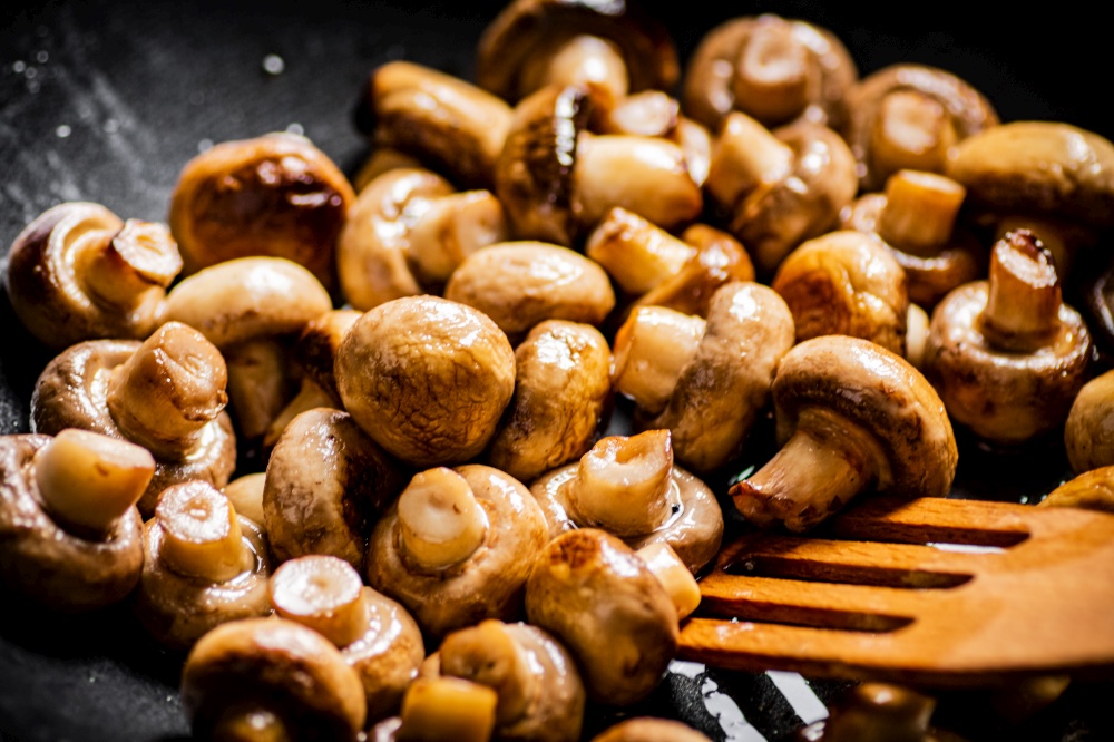 Mushrooms are fried in a frying pan. Macro background. High quality photo. Mushrooms are fried in a frying pan.