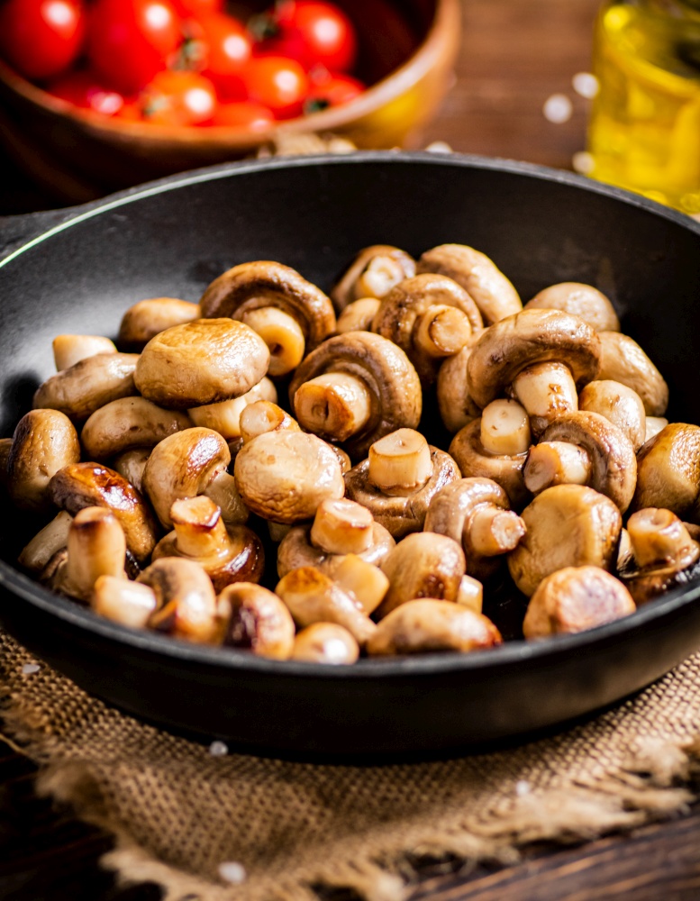 Homemade fried mushrooms in a frying pan. On a rustic background. High quality photo. Homemade fried mushrooms in a frying pan.