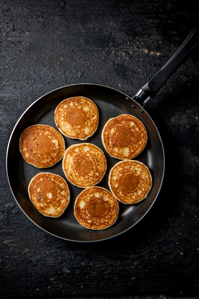 Homemade pancakes in a frying pan. On a black background. High quality photo. Homemade pancakes in a frying pan.