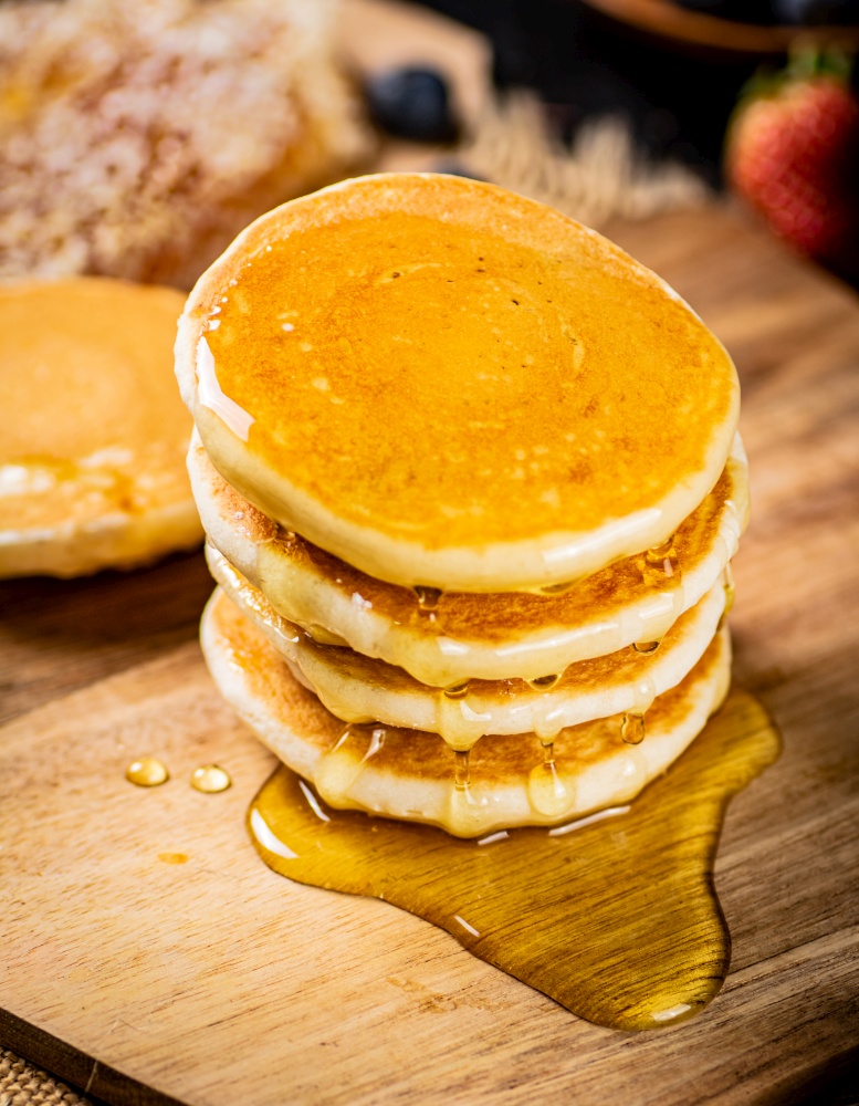 Homemade pancakes with honey on the table. On a wooden background. High quality photo. Homemade pancakes with honey on the table.