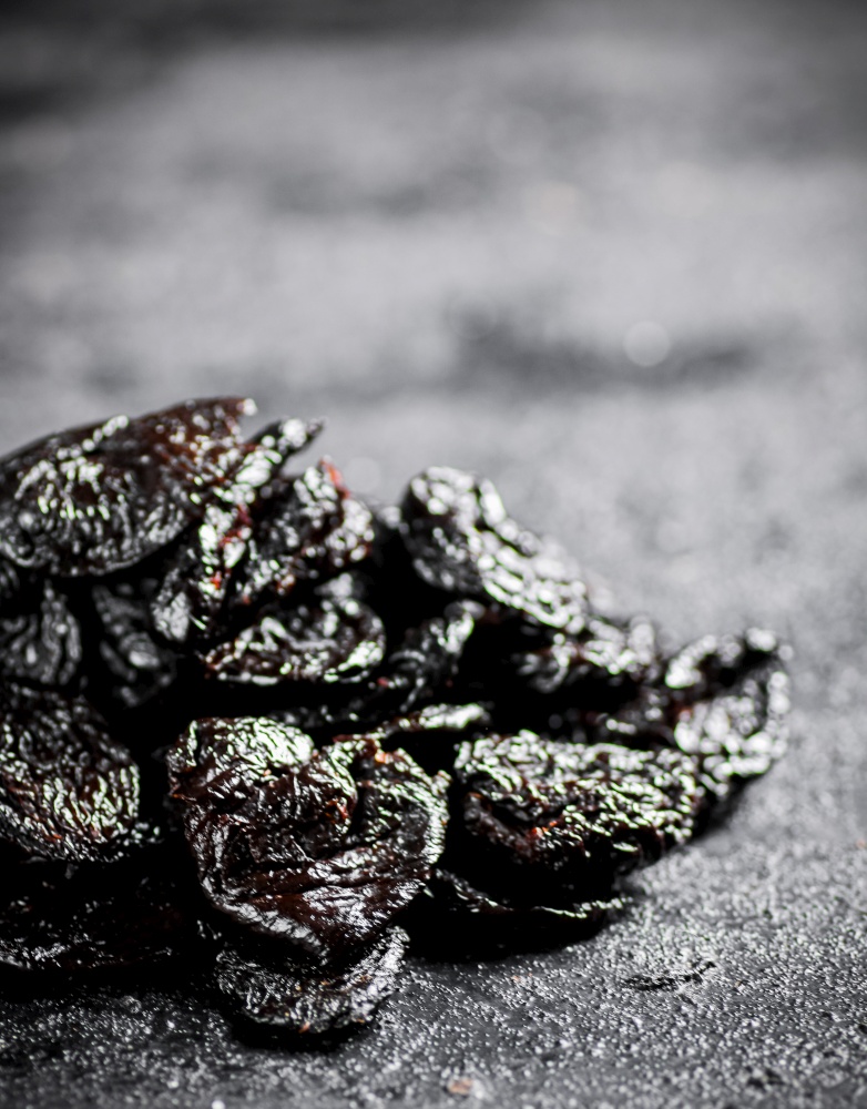 A bunch of prunes on the table. On a black background. High quality photo. A bunch of prunes on the table.
