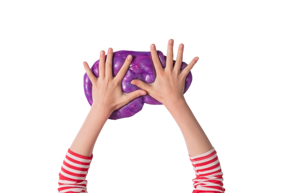 Child hands and purple shiny slime. Child girl plays with slime isolated on white. Home educational games concept. Top view, flat lay banner. Child hands and purple shiny slime. Child girl plays with slime isolated on white. Home educational games concept. Top view, flat lay banner.