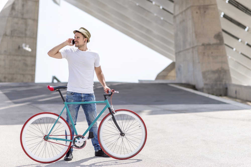 man using mobile phone and fixed gear bicycle in the street.