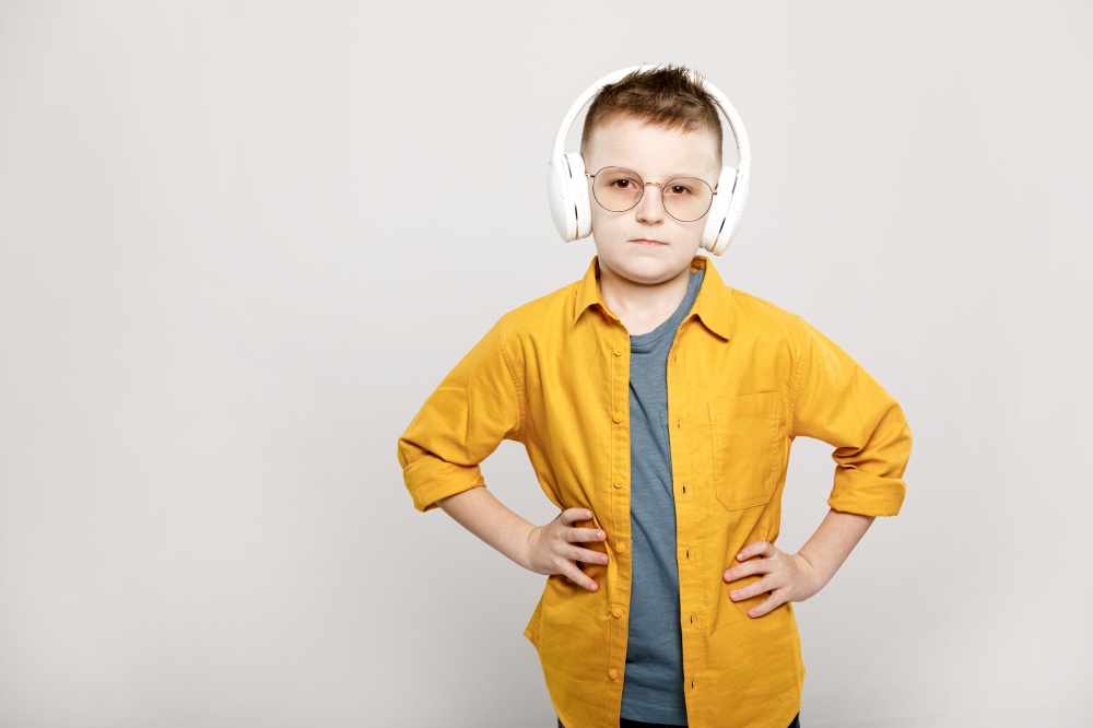 adorable child boy in white headphones and glasses isolated on grey background.. adorable child boy in white headphones and glasses isolated on grey background