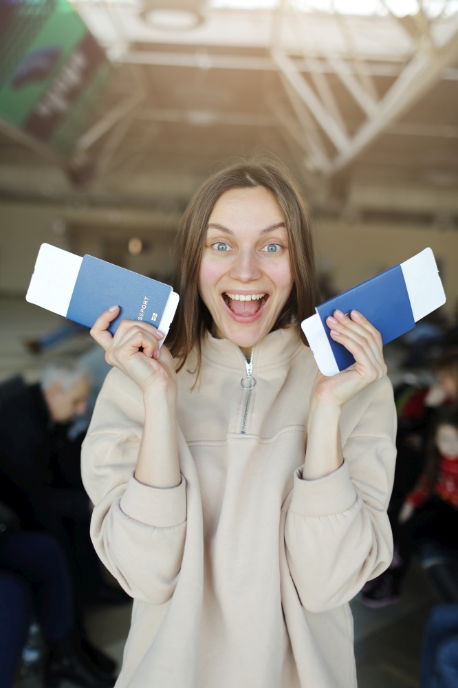 young beautiful woman is holding travel tickets and passports, happy girl looking at camera in airport terminal. summer travel vacation.. young beautiful woman is holding travel tickets and passports, happy girl looking at camera in airport terminal. summer travel vacation
